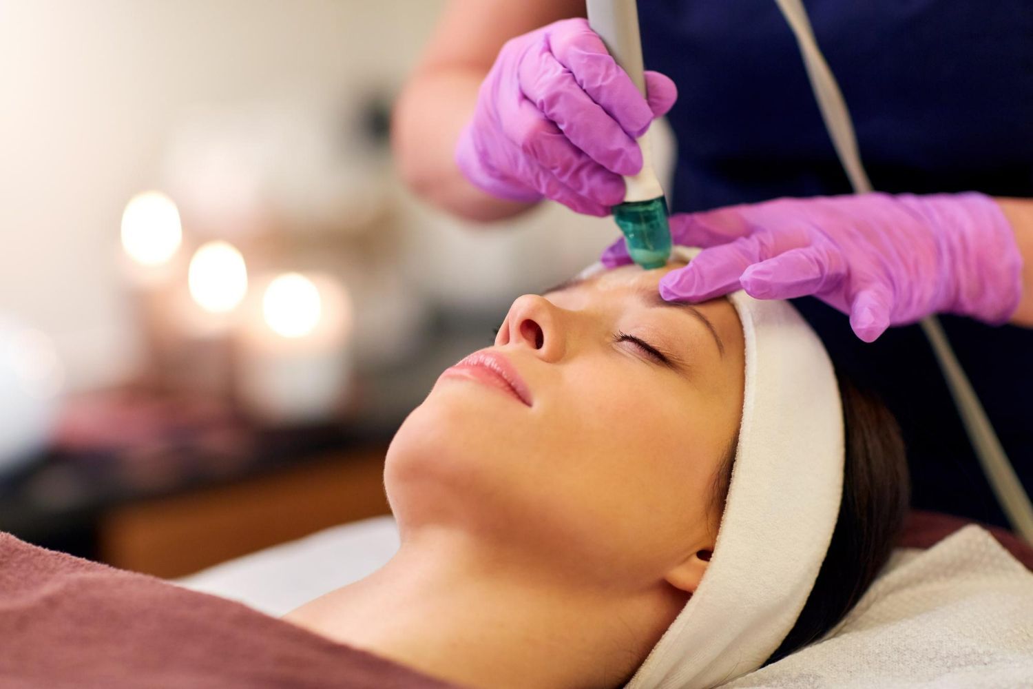 Esthetician applying green facial treatment to a client during a spa facial massage