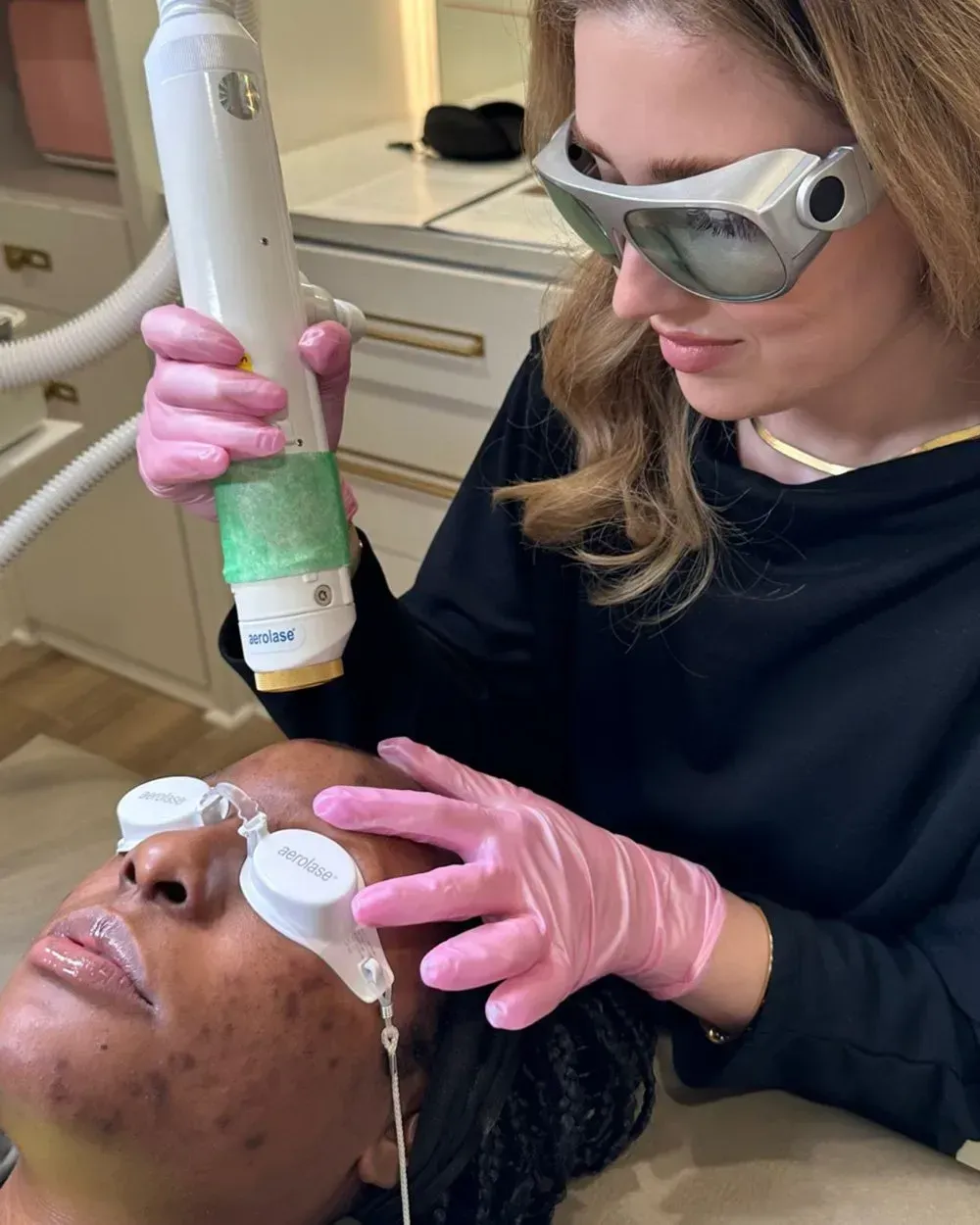 A woman is using a laser on a man 's face.