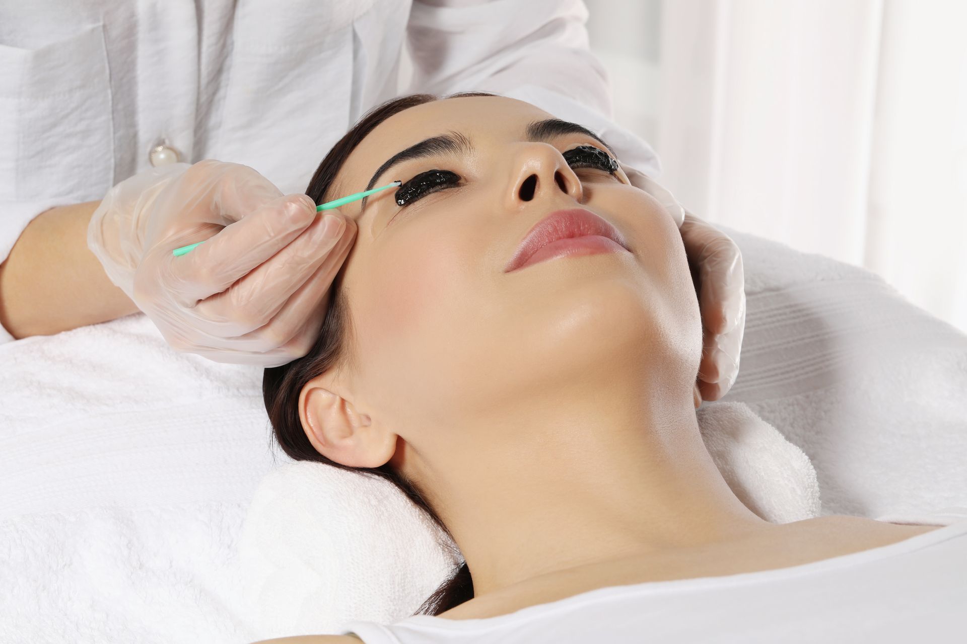 A woman is getting her eyelashes done at a beauty salon.