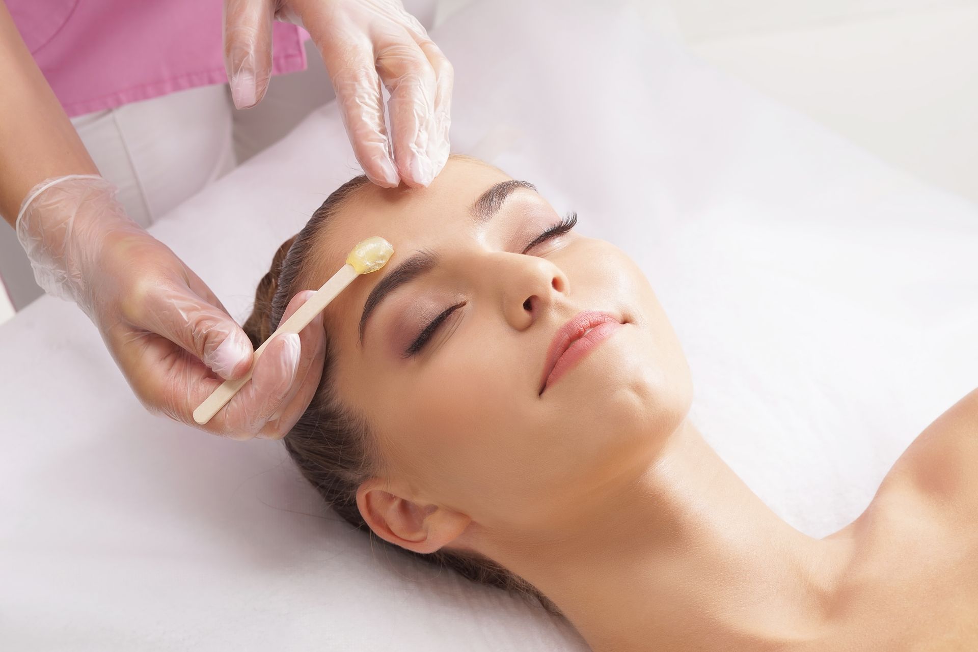 A woman is getting her eyebrows waxed in a beauty salon.