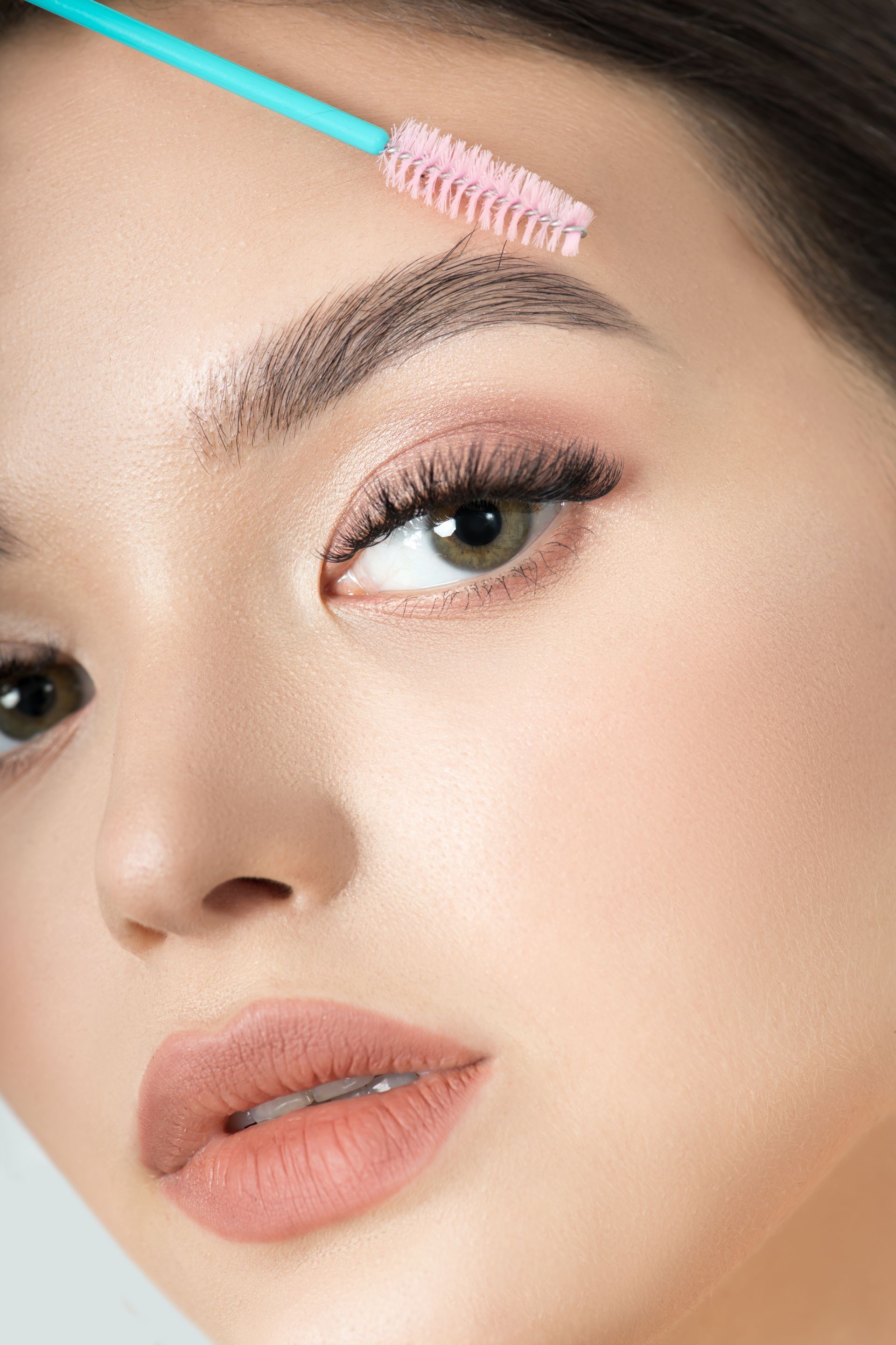 A close up of a woman 's face with a brush on her eyebrows.