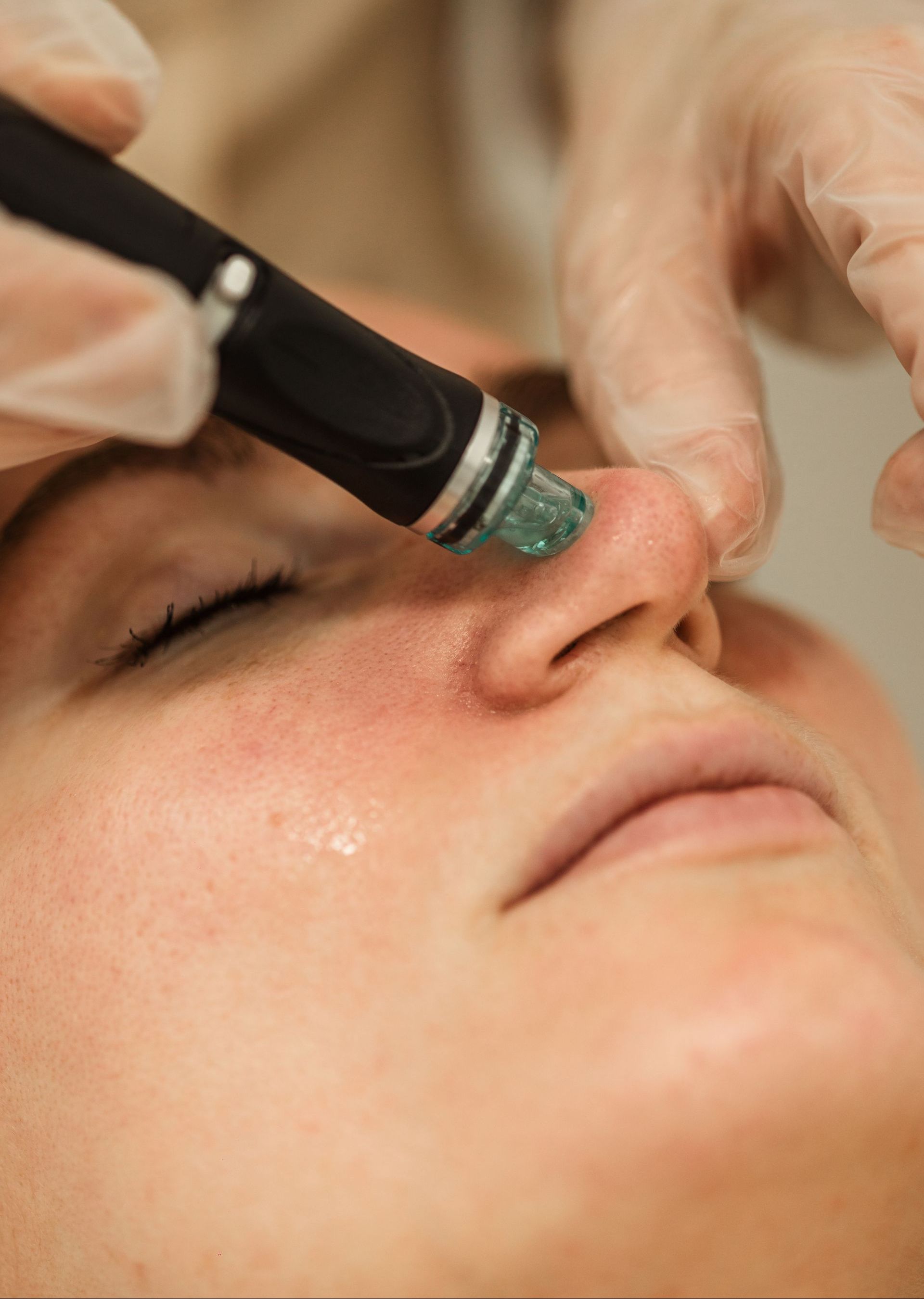 A woman is getting a facial treatment on her nose.