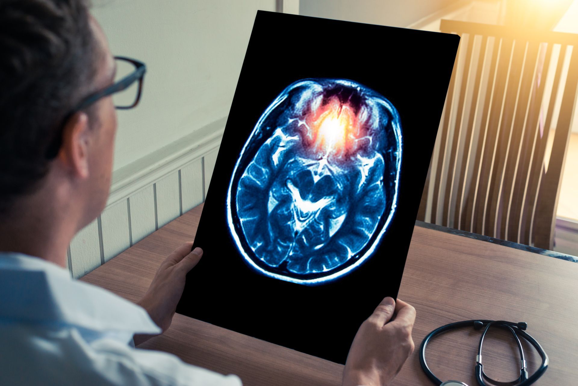 A man is holding a picture of a brain with a red spot in the middle.