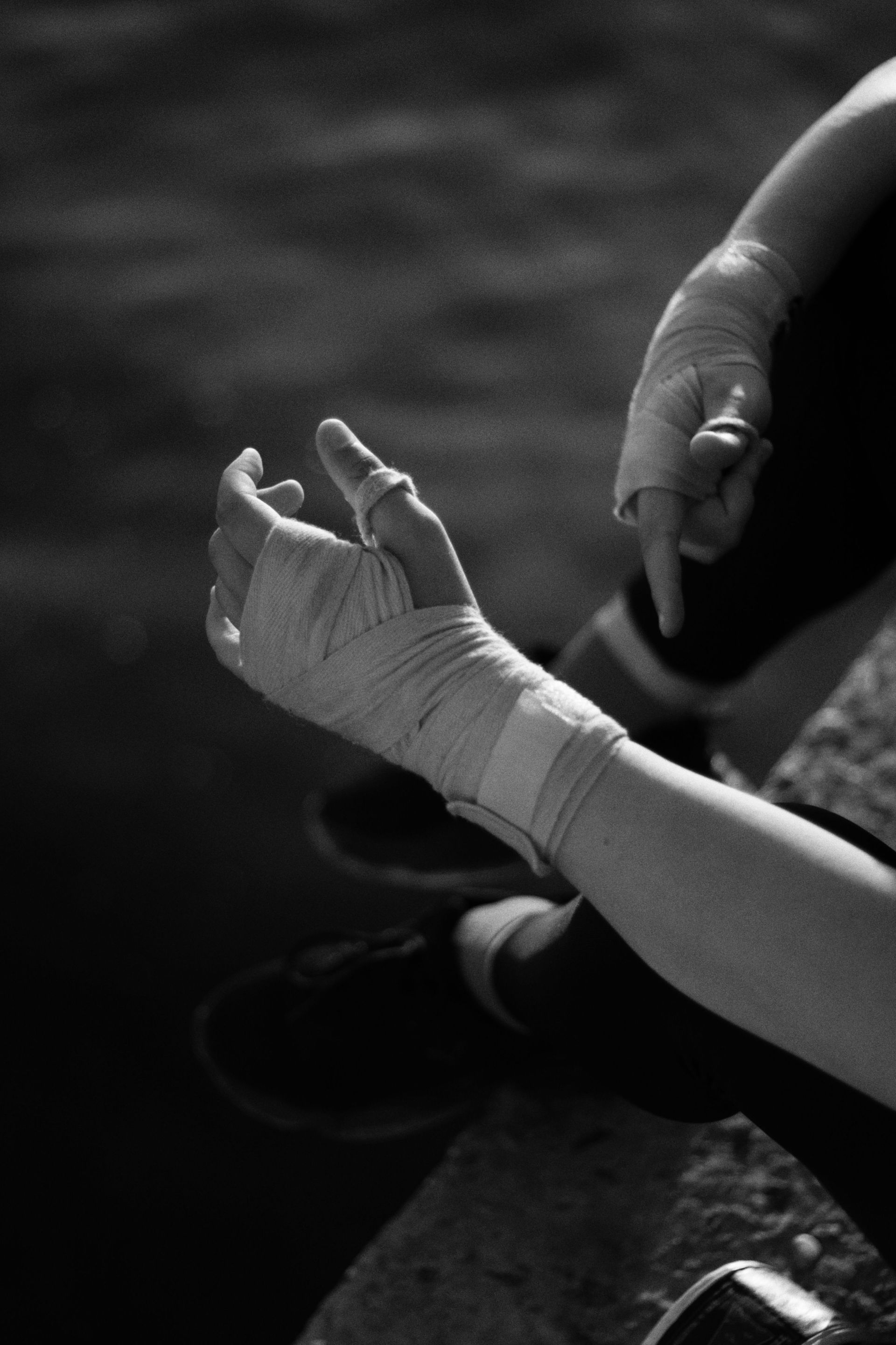 Bandaged hand resting in another person's grasp, with a blurred background.