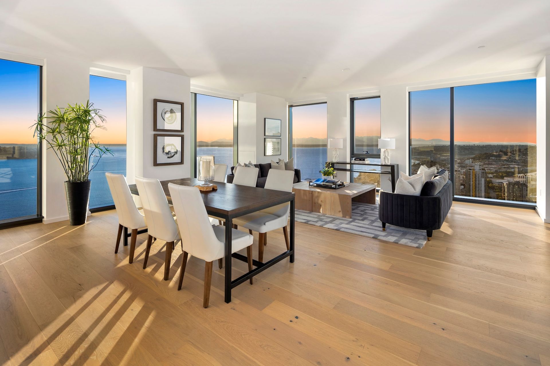Bright modern dining and living room with large windows, city view, and wood floors