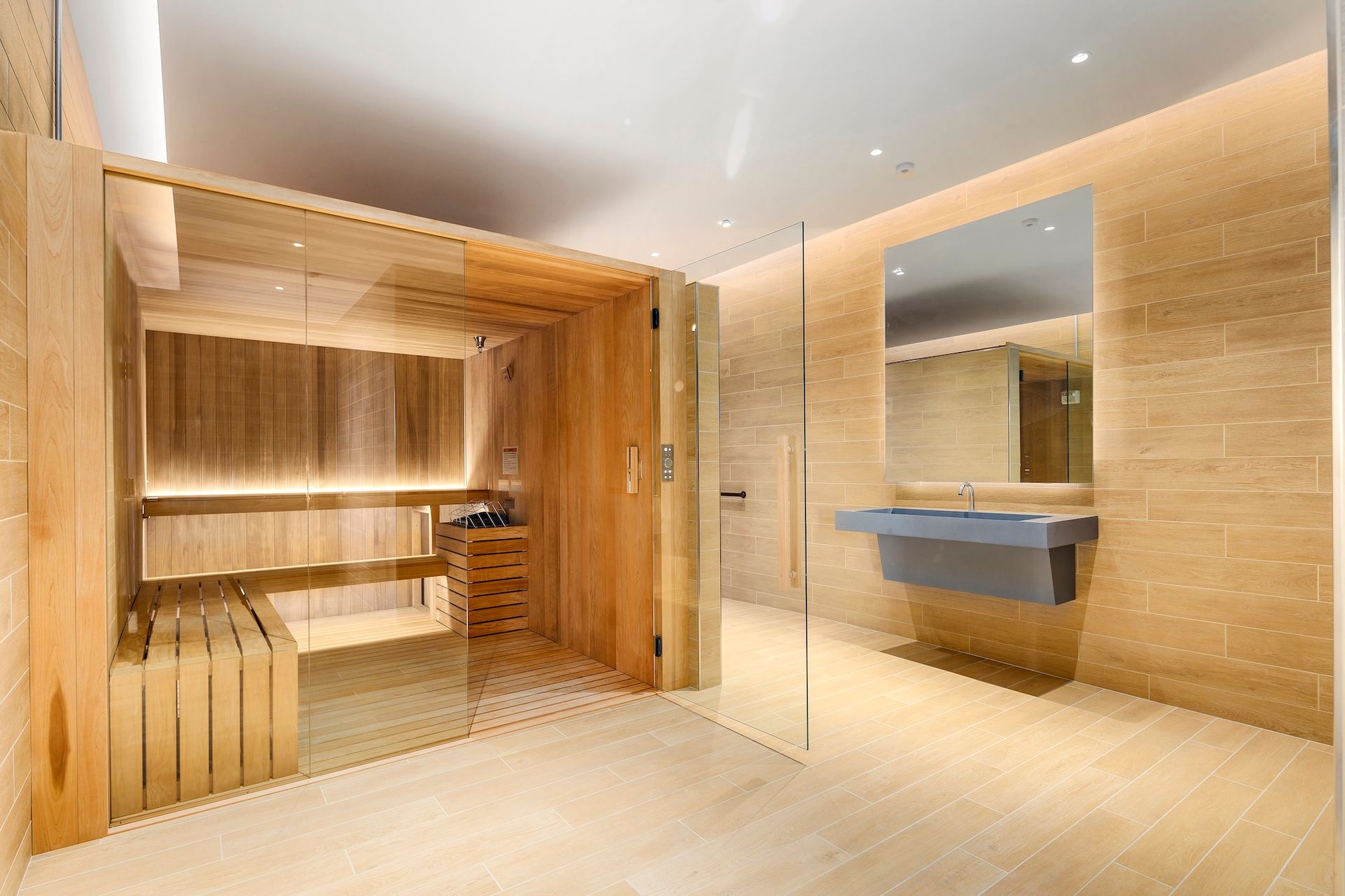 Modern spa interior with warm wood sauna, tiled walls, and a blue sink under a mirror