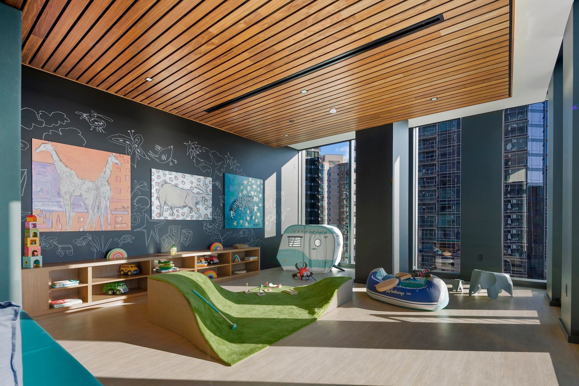 Modern lounge with curved green sofas, wood ceiling, map wall art, and city view through large windows