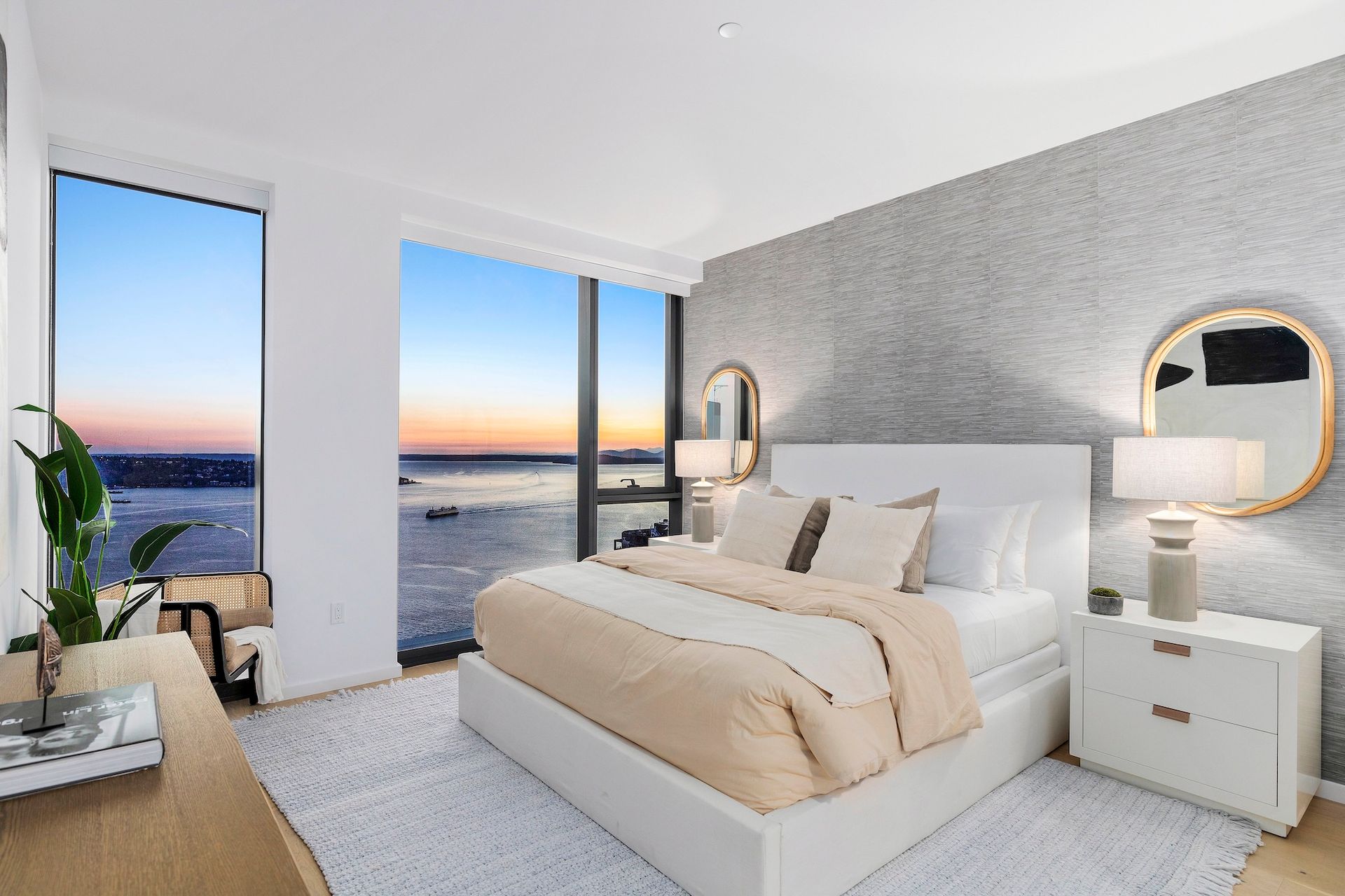 Modern bedroom with king bed, floor-to-ceiling windows, and ocean sunset views