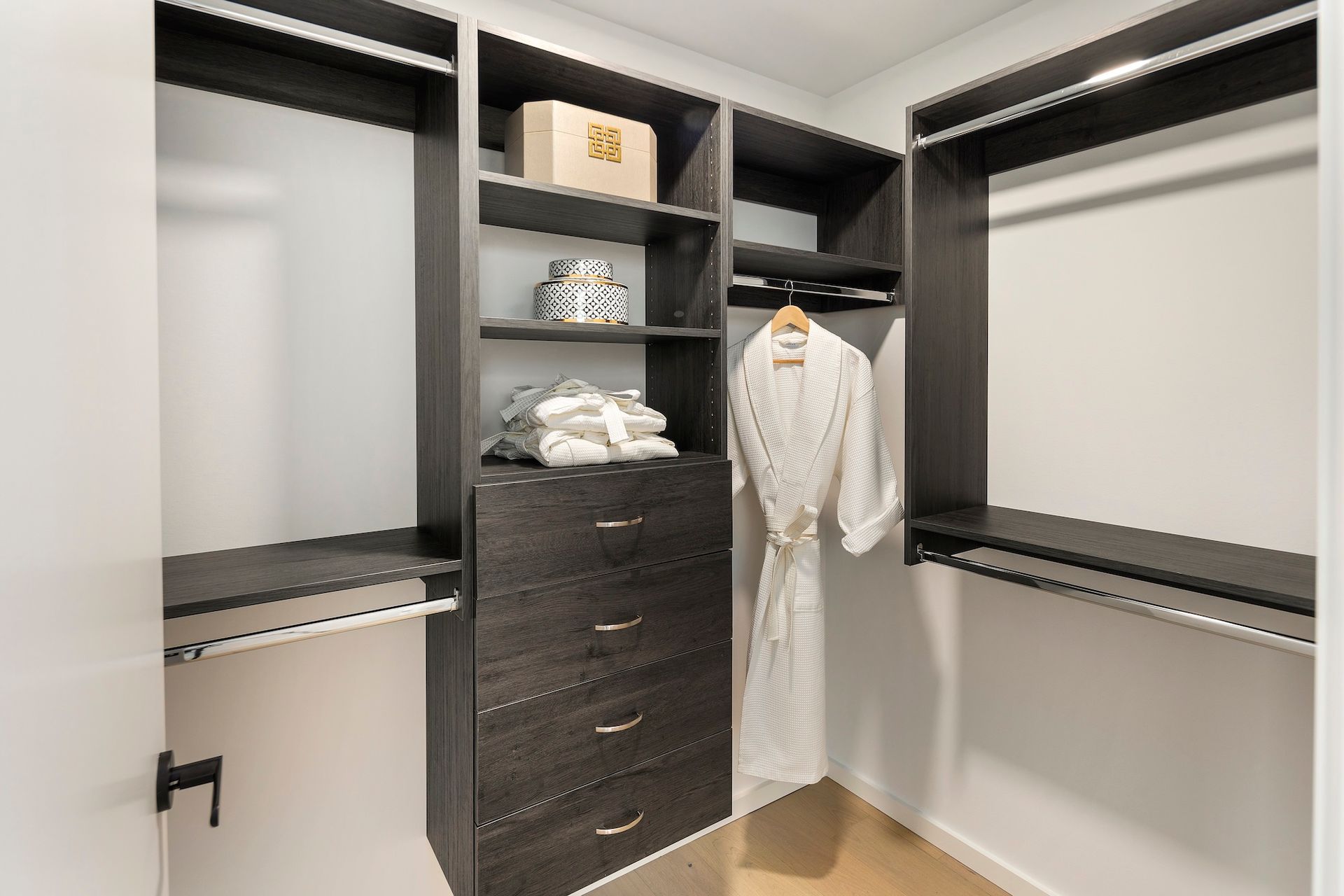 Walk-in closet with open shelving, drawers, hanging rods, and white robe hanging inside