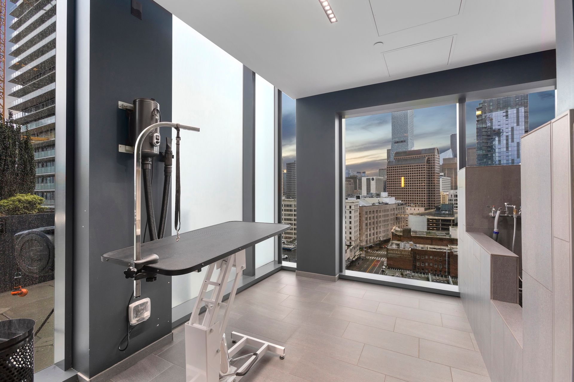 Modern exam room with exam table, medical equipment, and large window overlooking city buildings