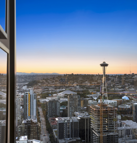 Seattle skyline at sunset with the Space Needle against a blue-orange sky.