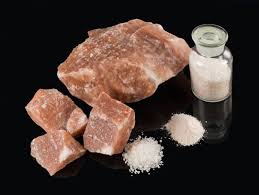 A pile of rocks and a bottle of salt on a black surface.