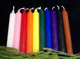 A row of candles of different colors are sitting next to each other on a table.