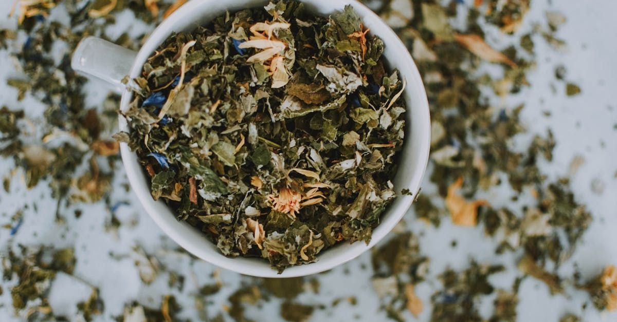 A bowl of dried herbs with a spoon in it on a table.