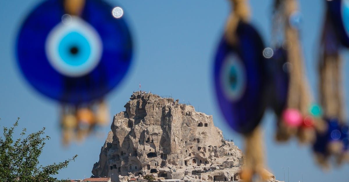 Evil eye decorations are hanging from a rope in front of a mountain.