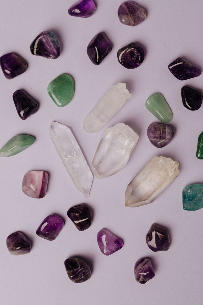 Assorted polished stones in purple, green, white, and clear on a light background