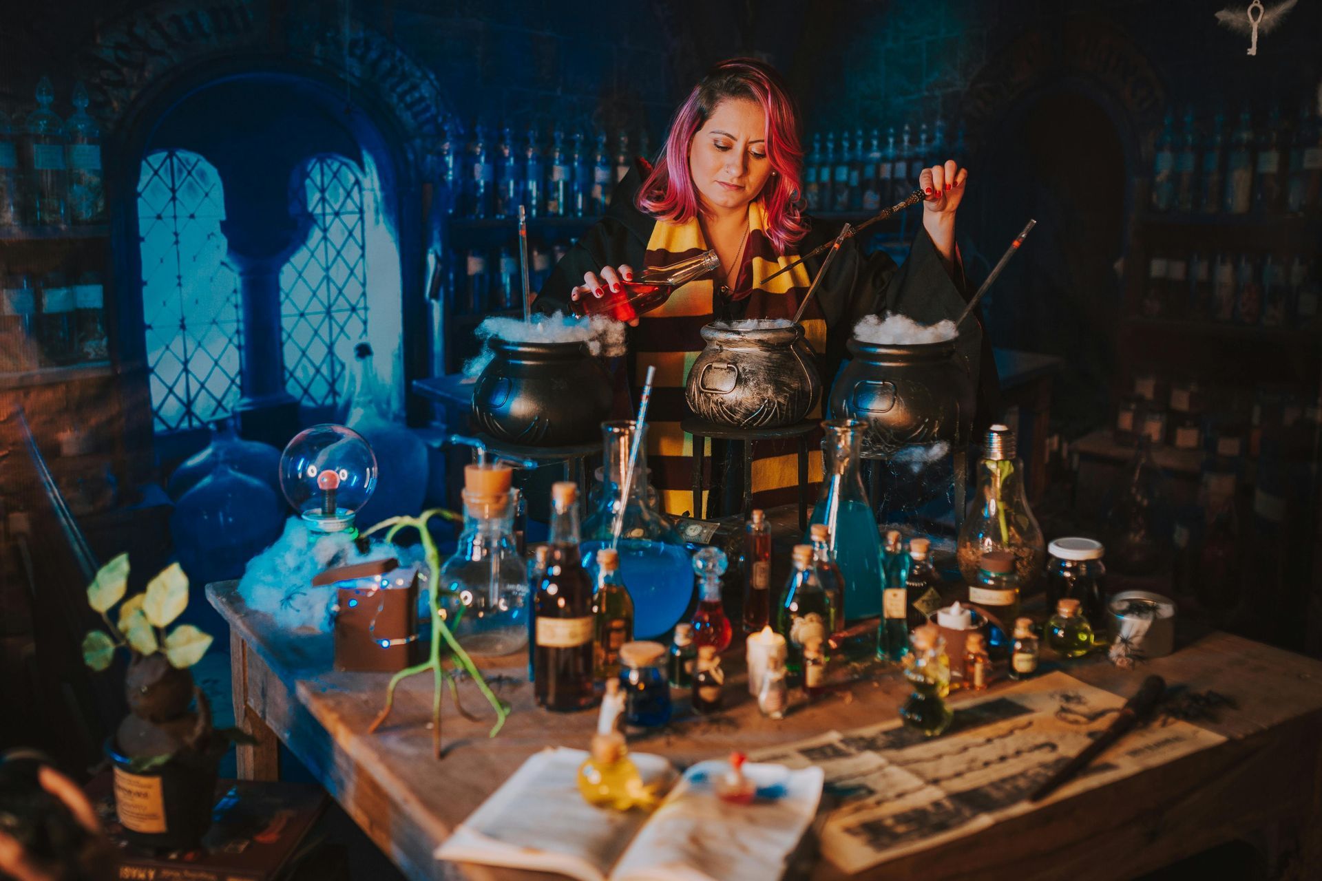 A person in a Hogwarts scarf stirs a potion in a bubbling cauldron, surrounded by potion bottles in a dim, mystical room.