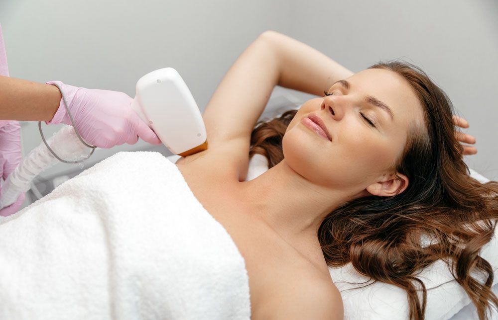 A woman is getting a laser hair removal treatment on her armpit.