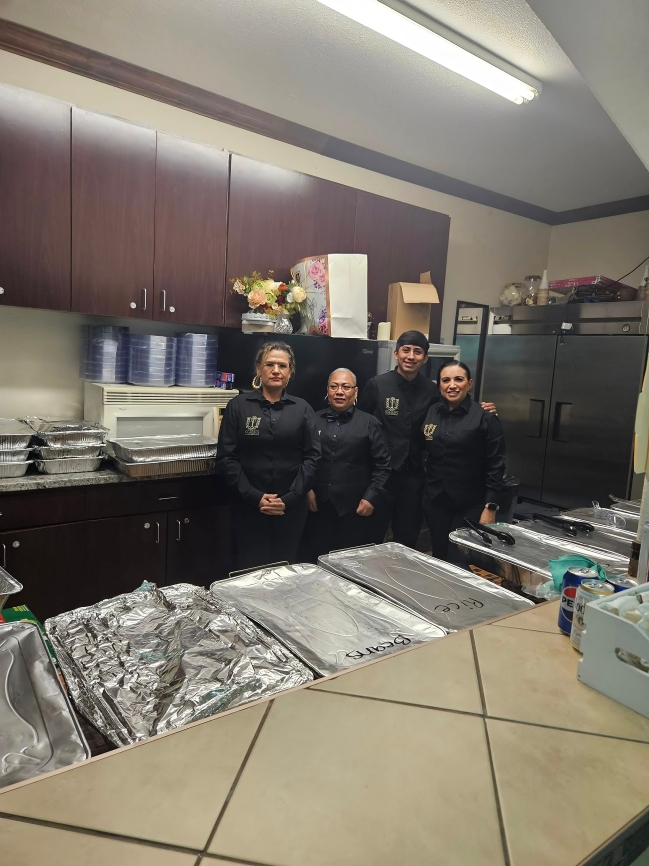 A group of people are posing for a picture in a kitchen.