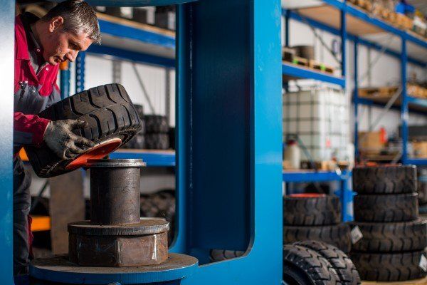 Un hombre está trabajando en un neumático en una máquina en un almacén.