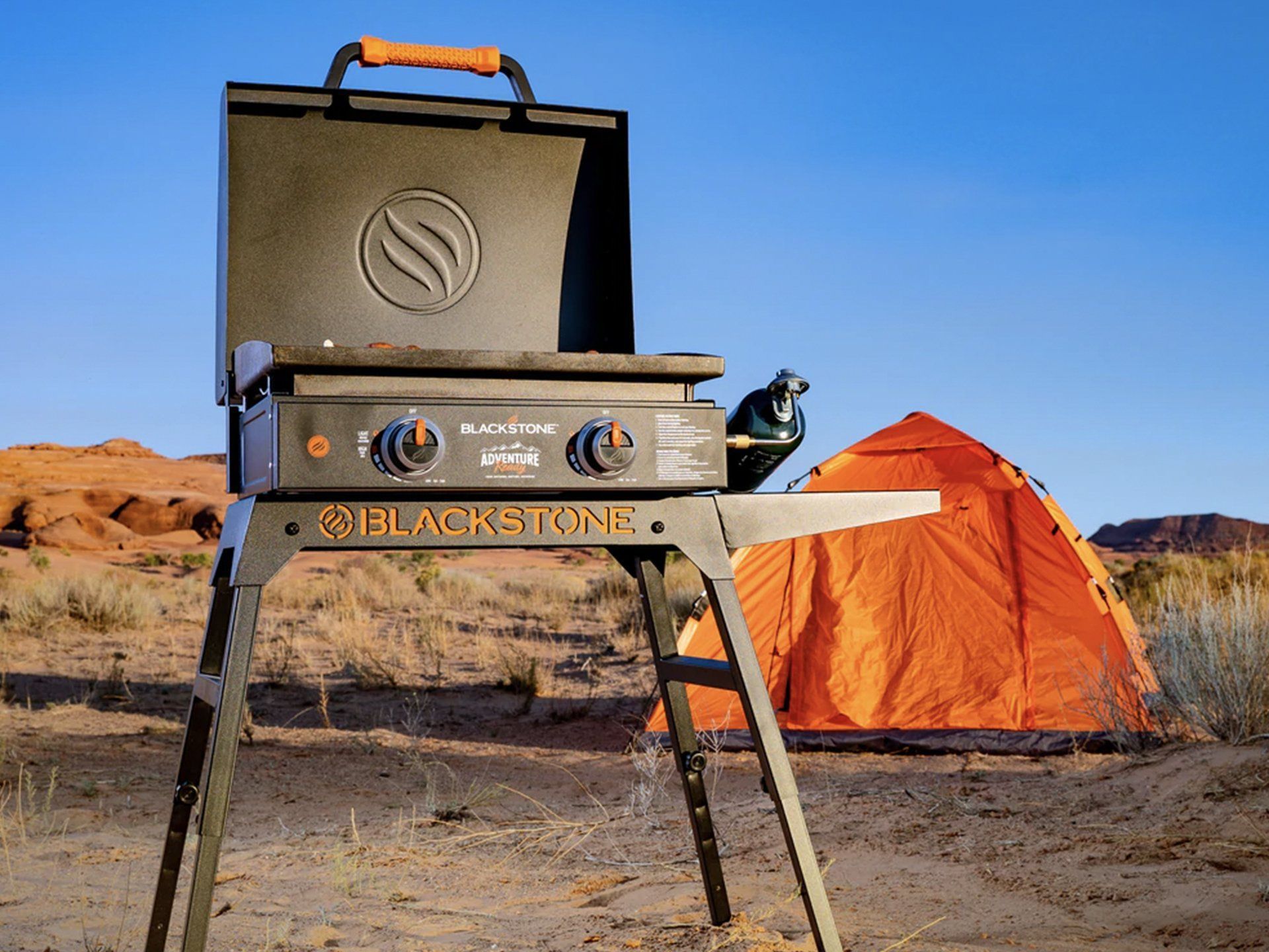 Blackstone portable grill on stand with tent in desert setting.