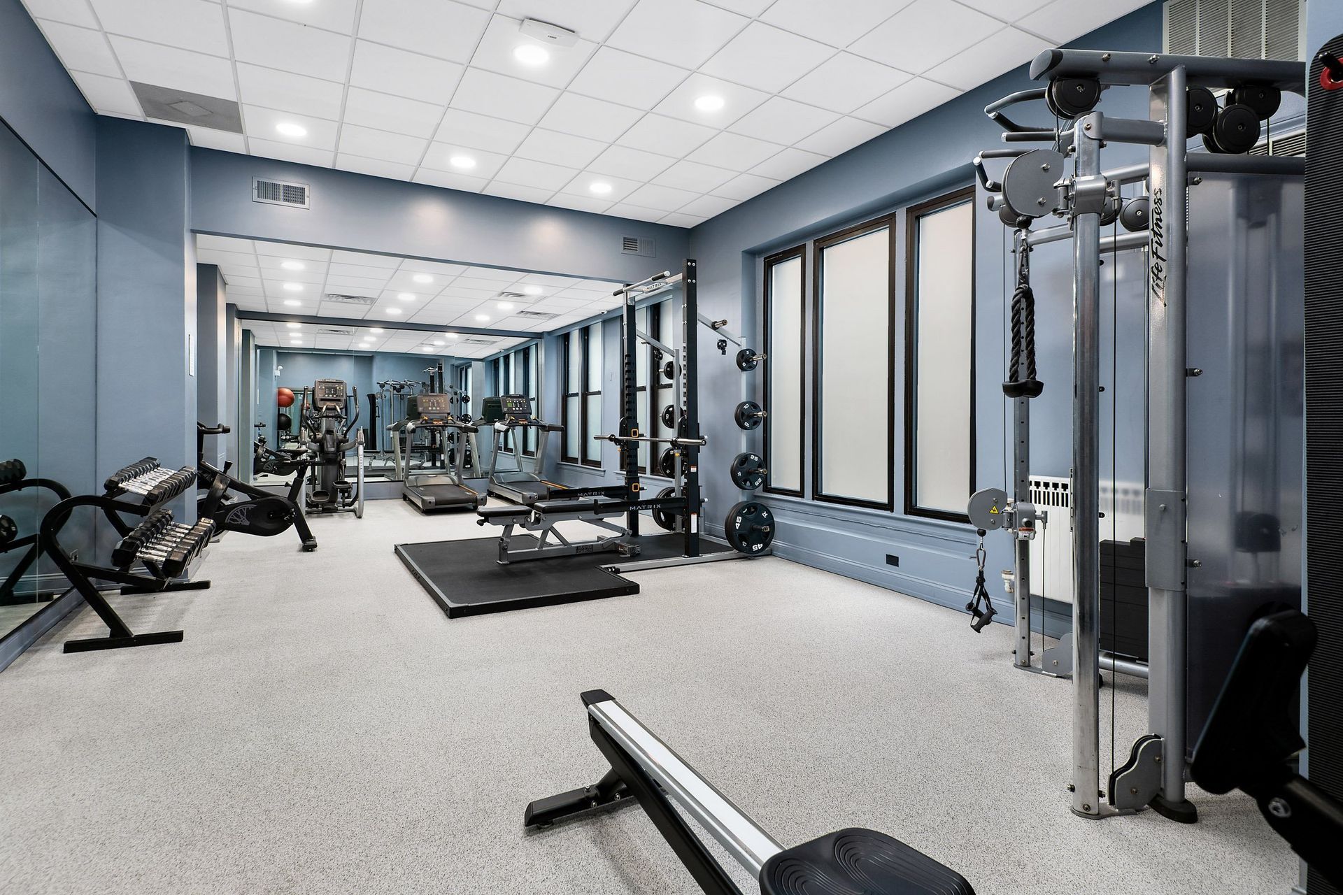 a spacious fitness room with cardio machines and weights