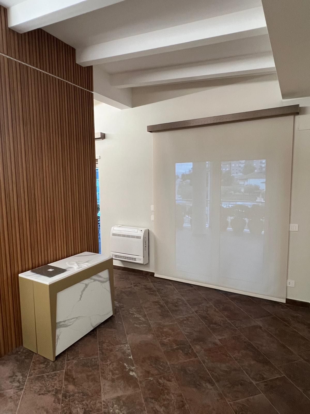 Stanza interna con pavimento marrone, una parete decorativa in legno e una tenda color crema.