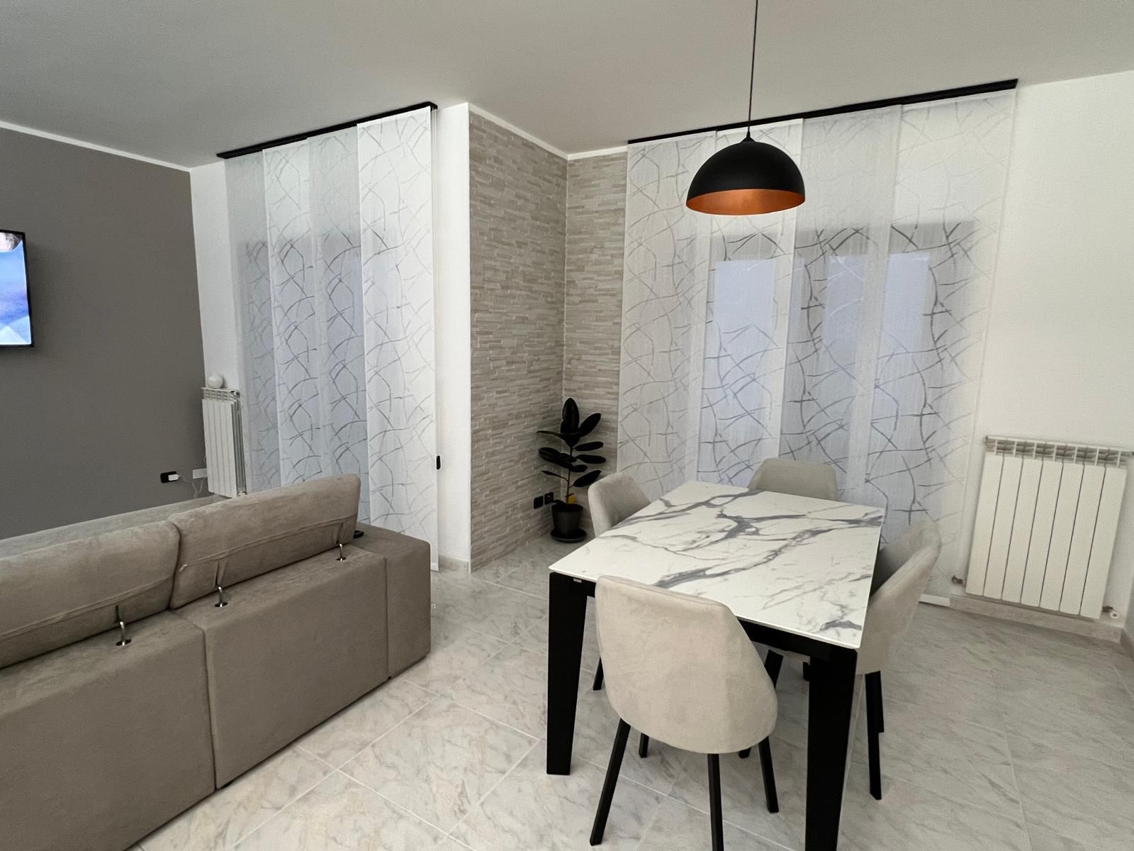 Moderna sala da pranzo con tavolo, sedie e tende trasparenti.