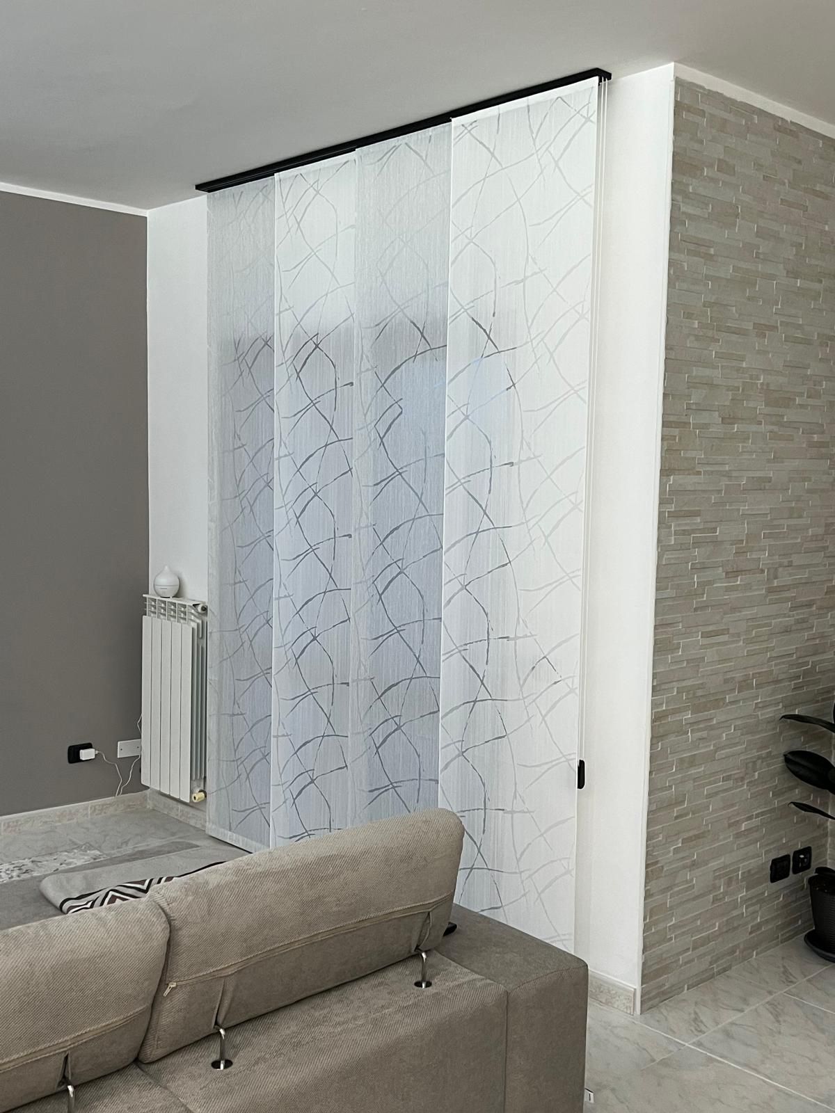 Soggiorno con pannelli trasparenti bianchi a motivi, utilizzati come divisori.