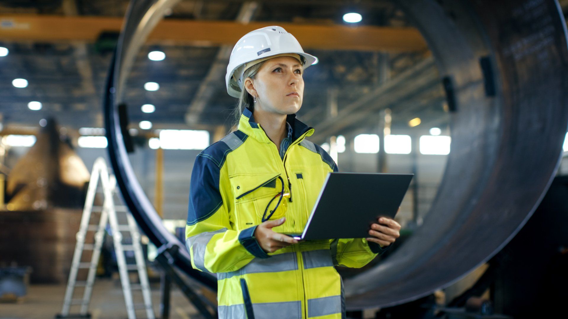 Civil Engineer (young woman) with hard hat, high viz and clipboard in aerospace manufacturing setting, representing Skilled Worker Visa applicants.