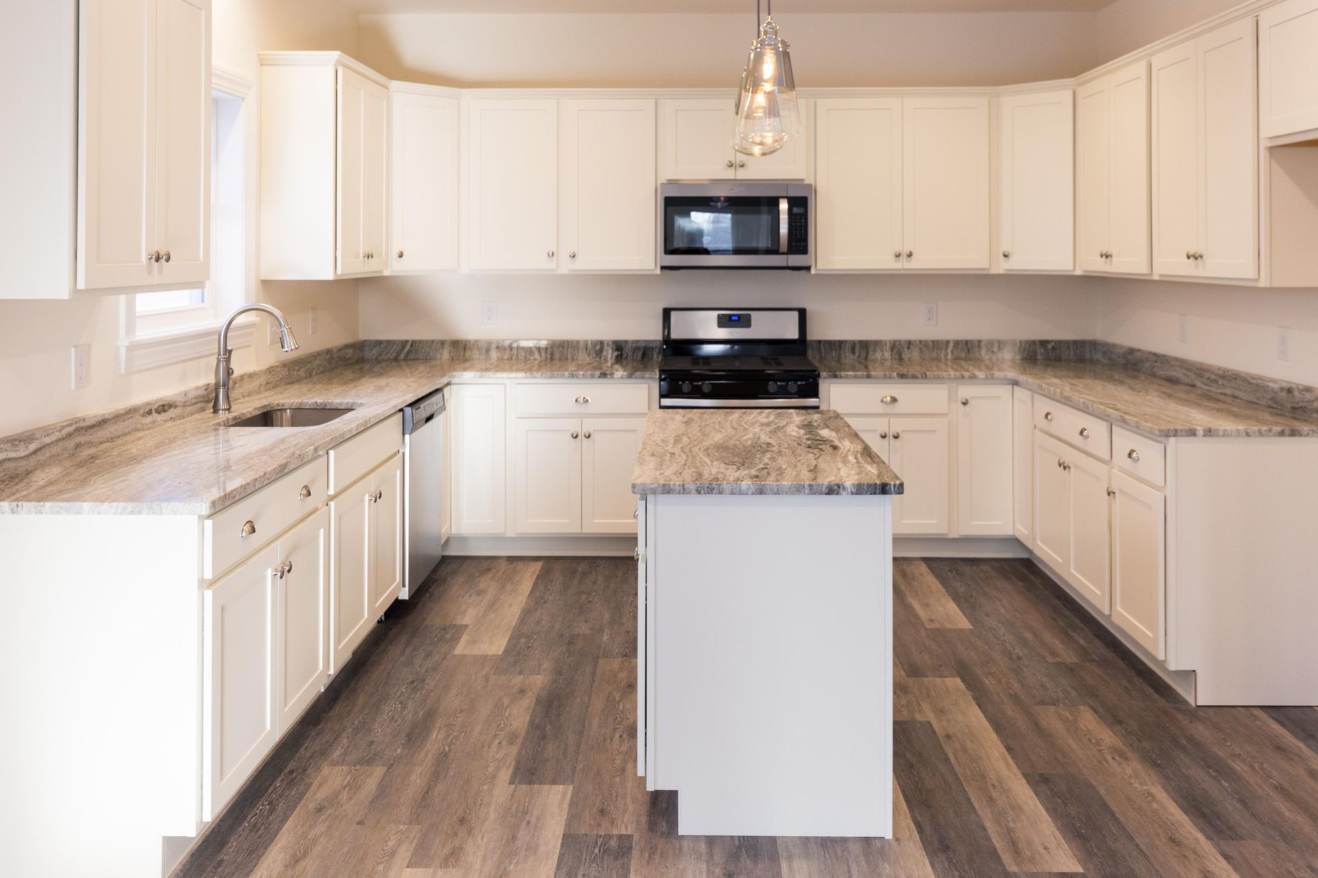 White kitchen with a U-shaped countertop, island, stainless steel appliances, and wood-look flooring.