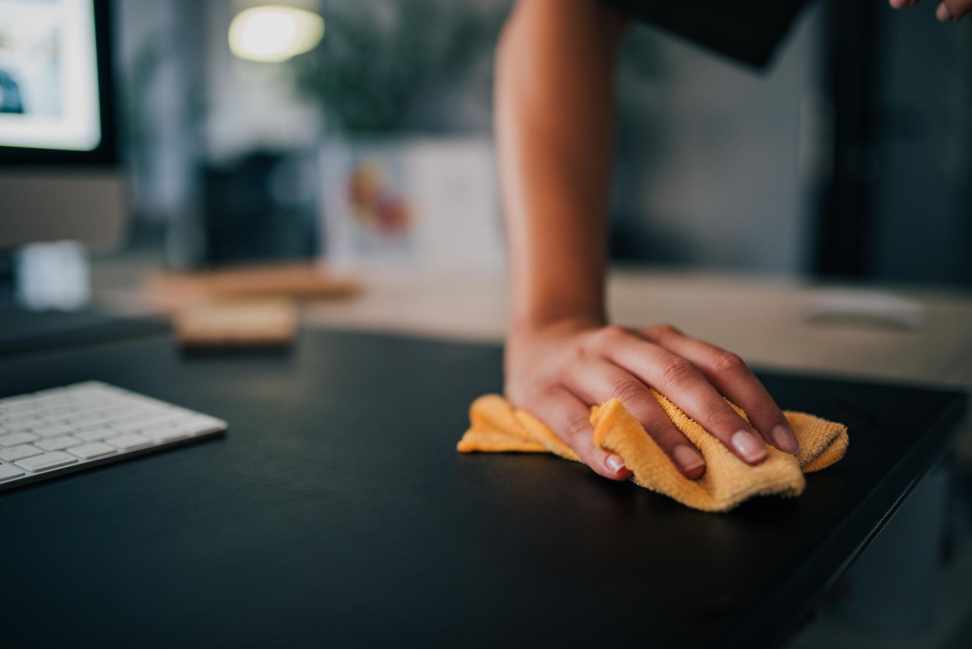 Person using hedge trimmer on a green bush near a brick wall.