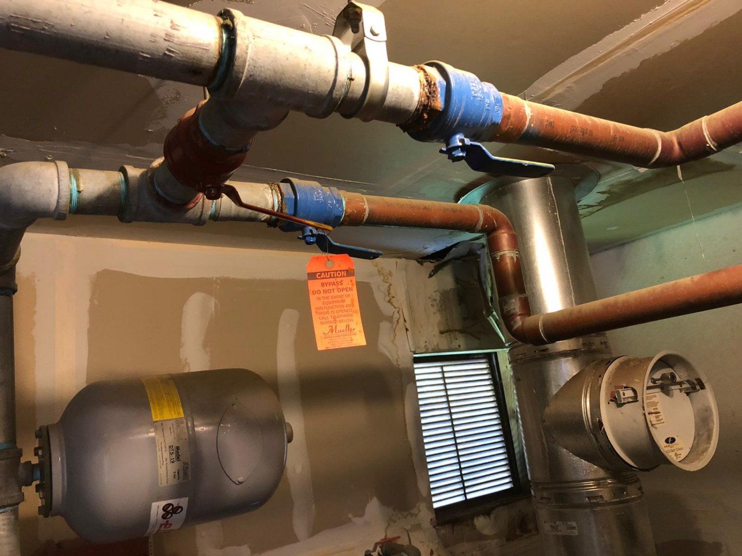 A room with a lot of pipes and a window.