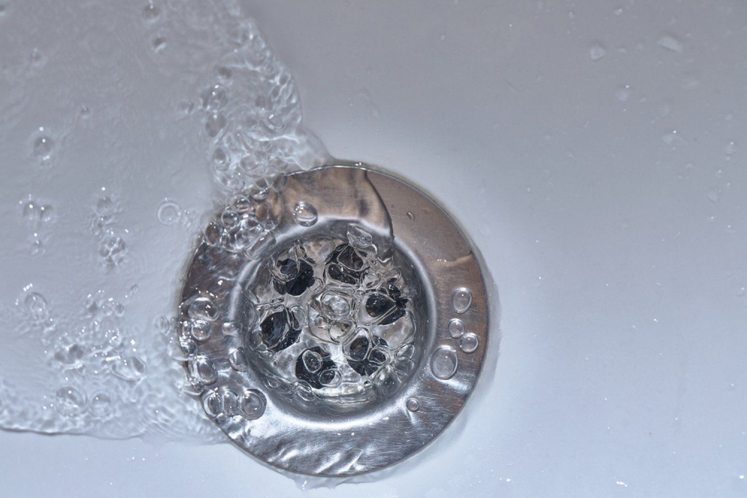 A close up of a sink drain with water running down it.