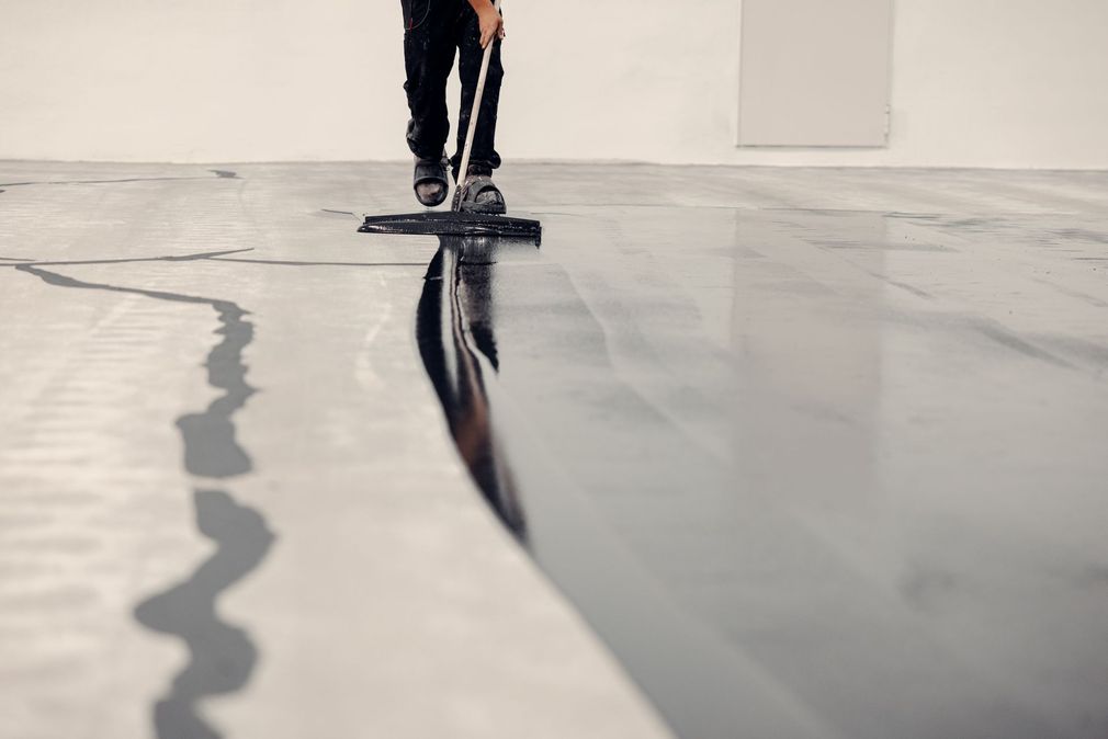 Person walking across a glossy floor with a dark reflection and a trailing wet streak