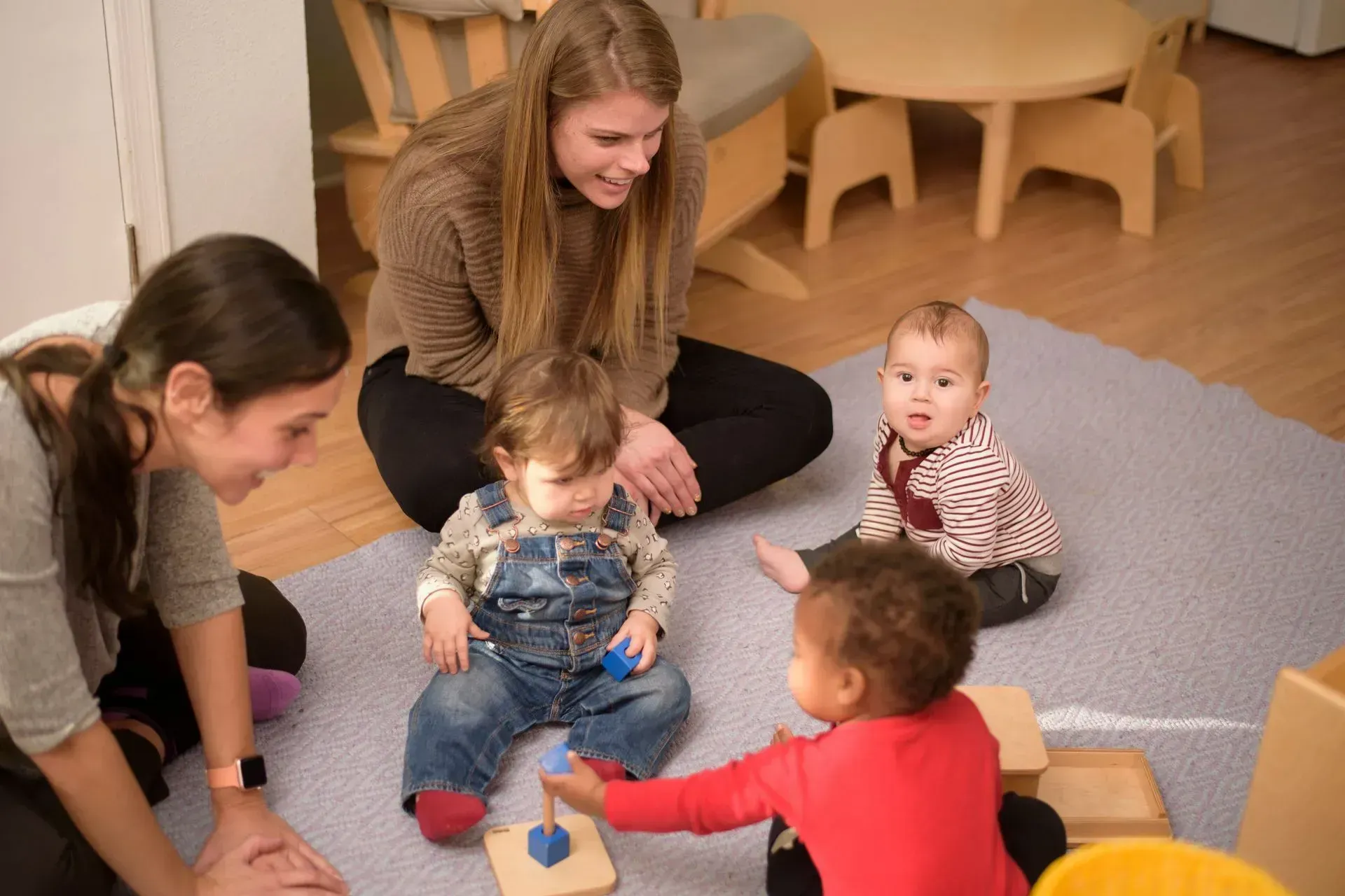 Infants and guides working with Montessori materials on the floor.
