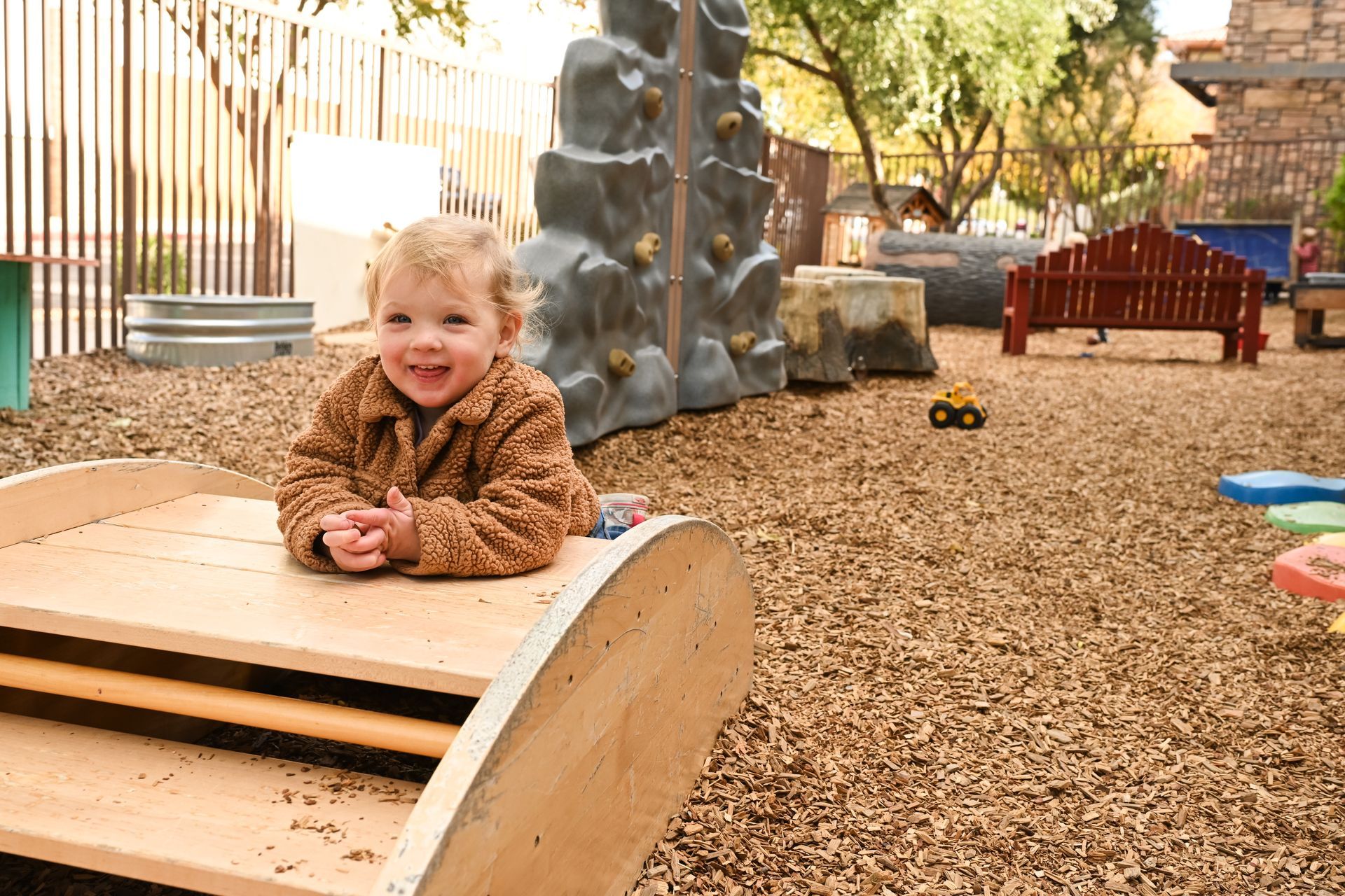 Montessori infant on a wooden bridge, playground background.