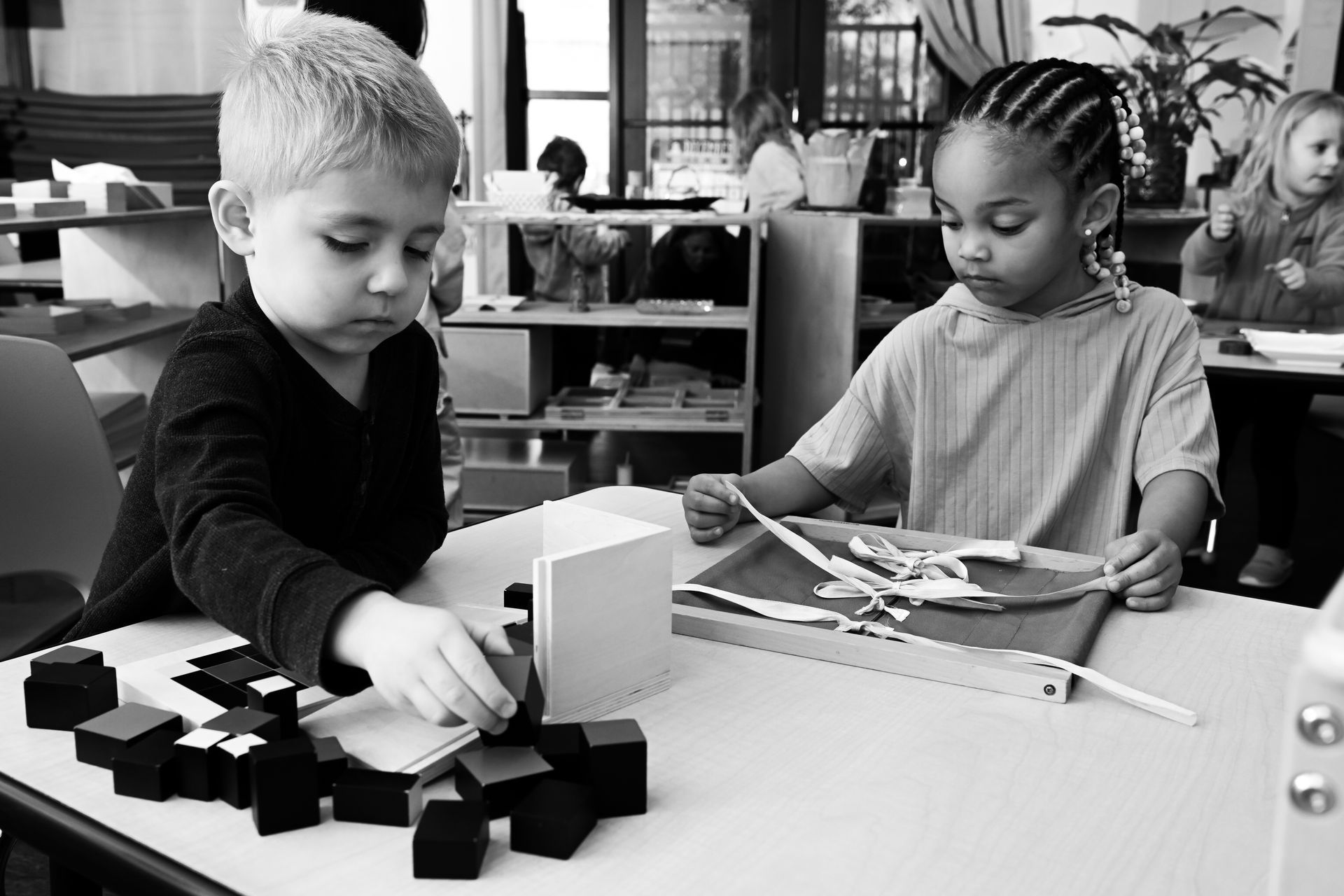 A group of Montessori children are working in the classroom with montessori materials.