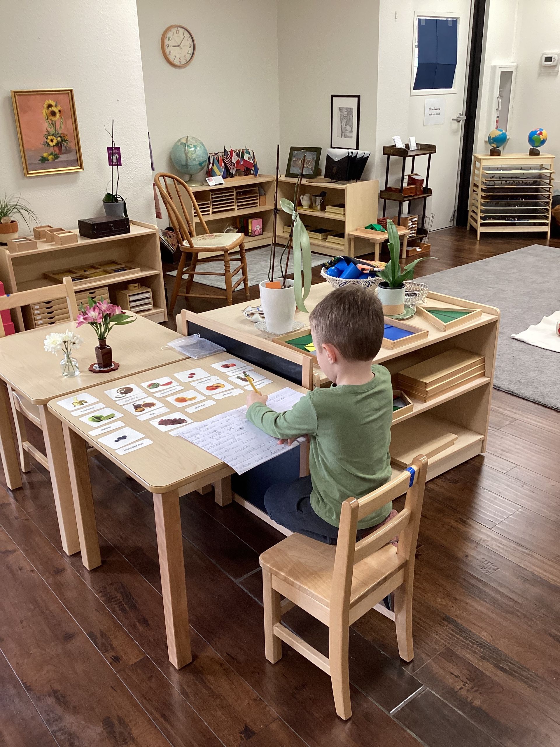 Montessori child sitting at a wooden table working with montessori materials.