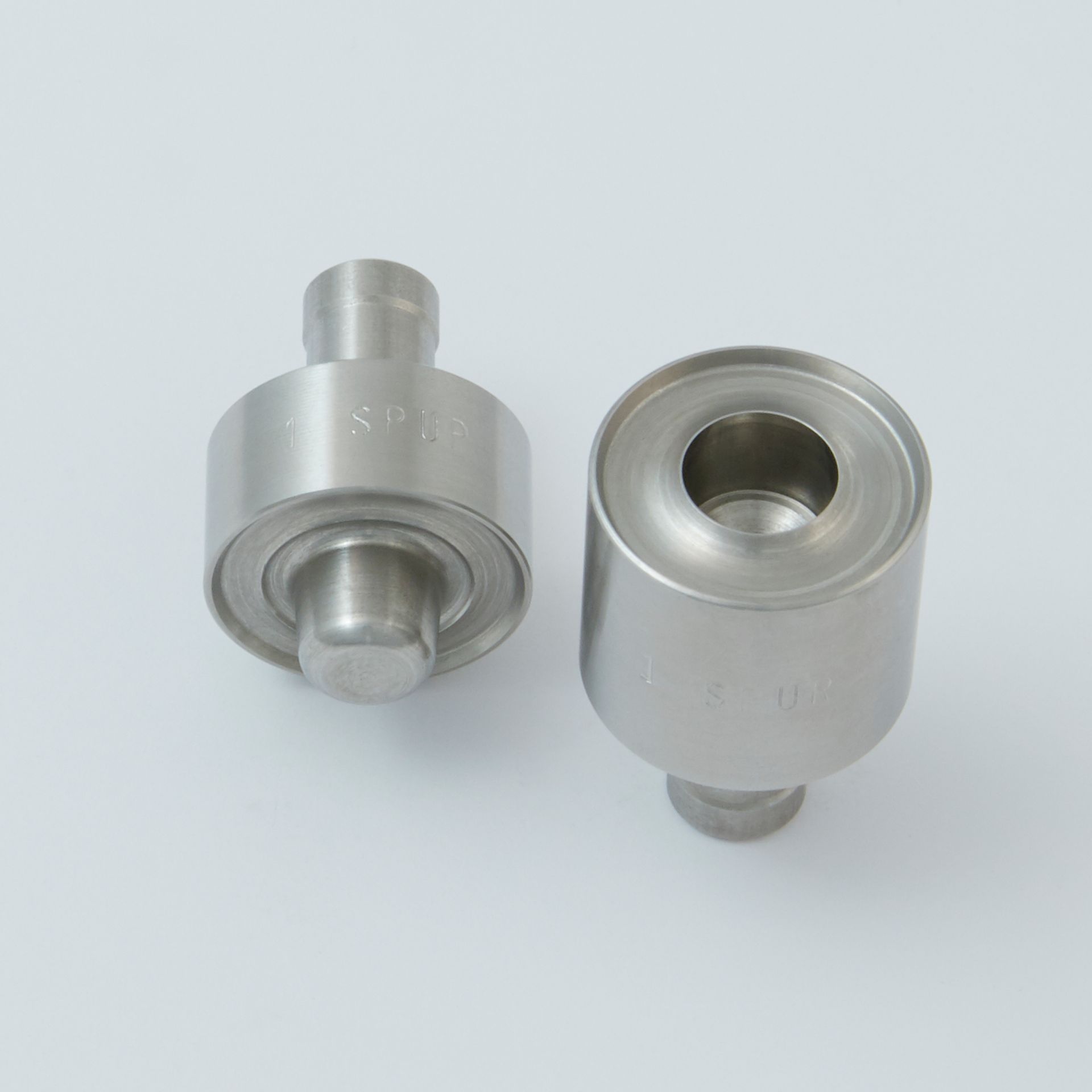 Two cylindrical metal industrial punch and die tools shown from different angles against a plain white background.