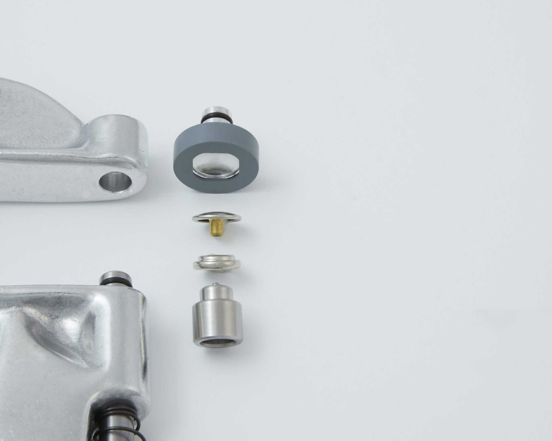 Exploded view of metallic components, including a washer, screw, and fastener parts, on a white surface.