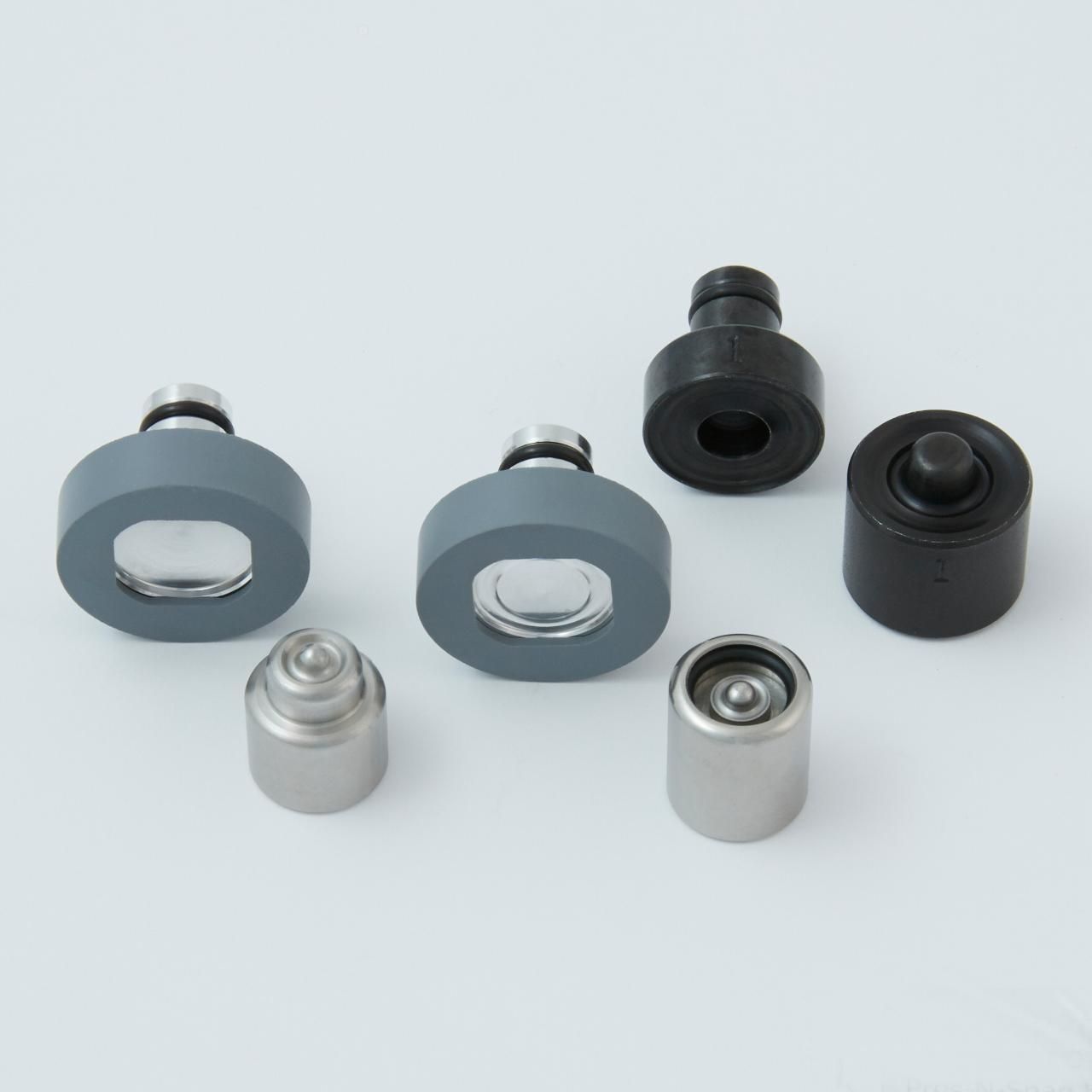 Various small industrial parts on a white surface, including round and cylindrical pieces.