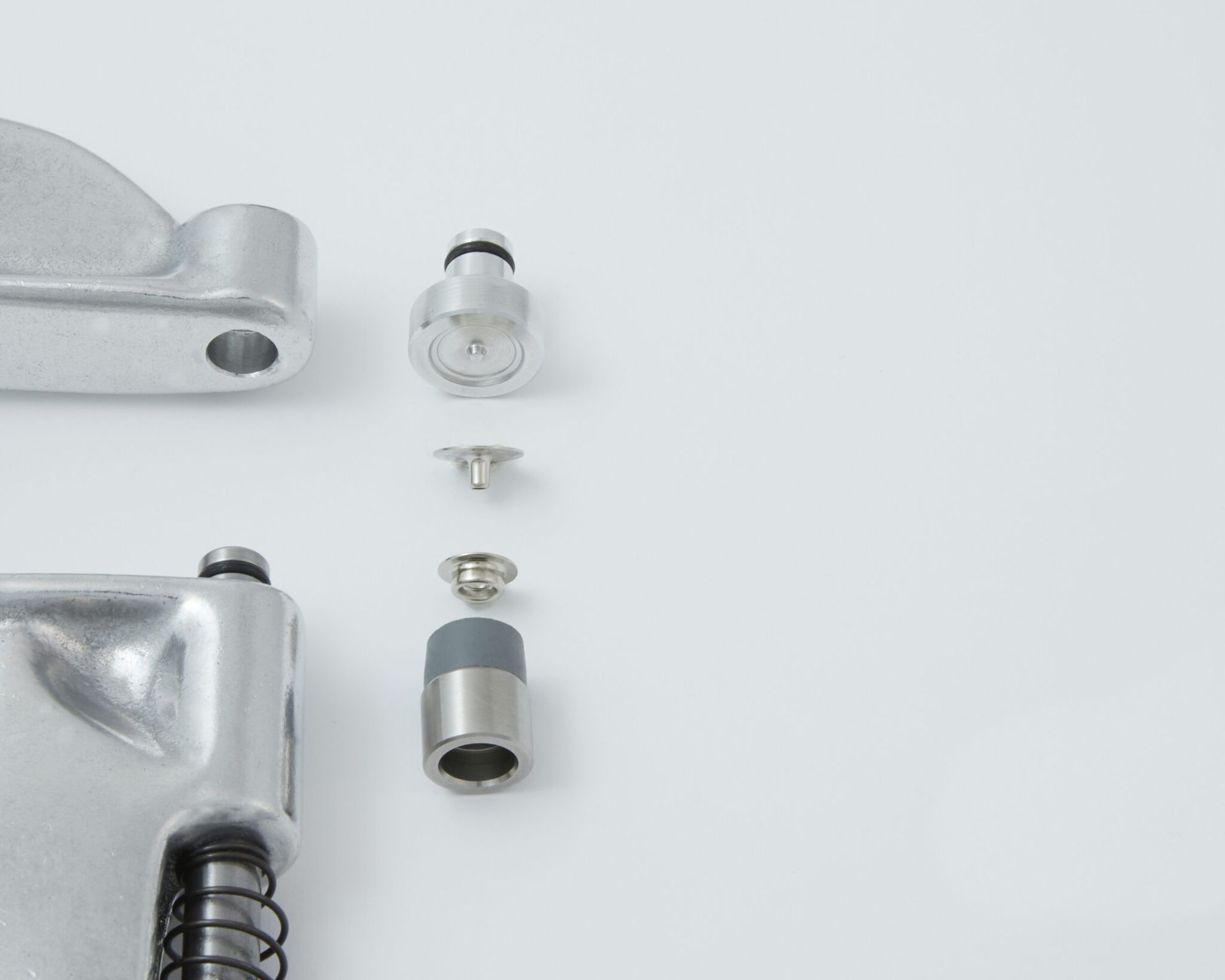 Parts of a metal rivet press laid out on a white surface, including tools and rivets.