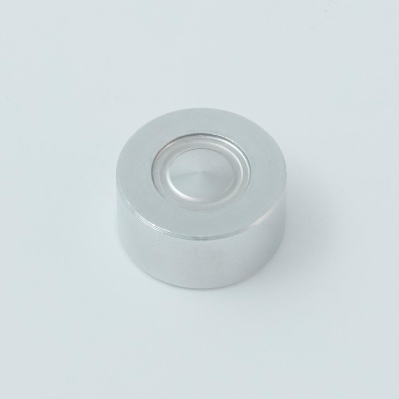Silver metal cap with a recessed center, likely for a vial or bottle, on a white surface.
