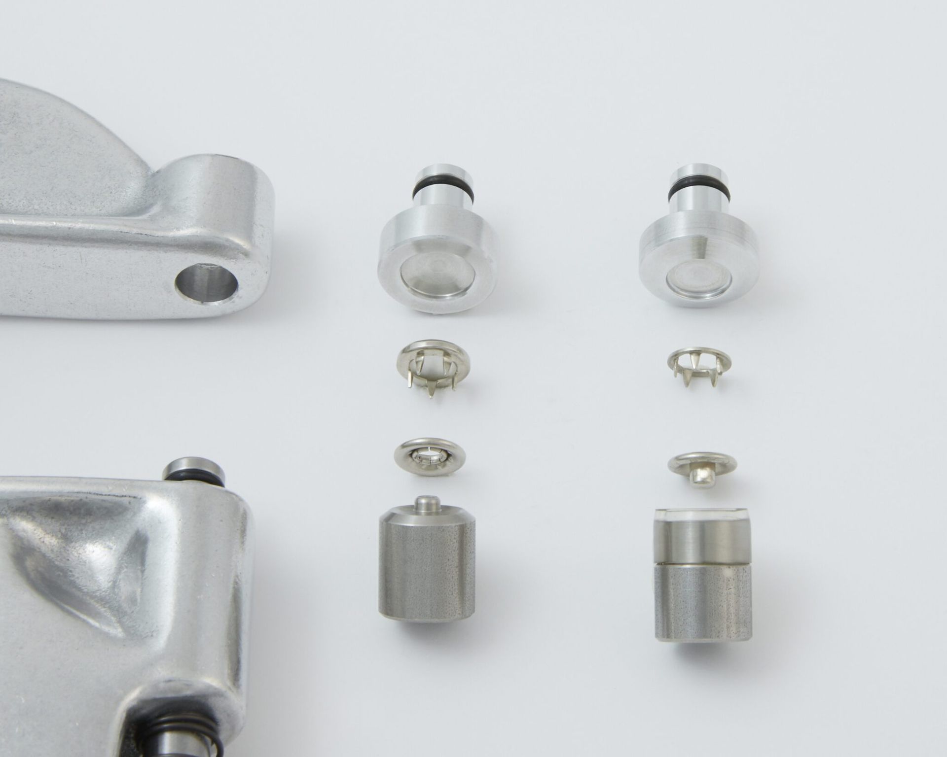 Metal hardware components: rivets, setting tools, and connecting pieces.