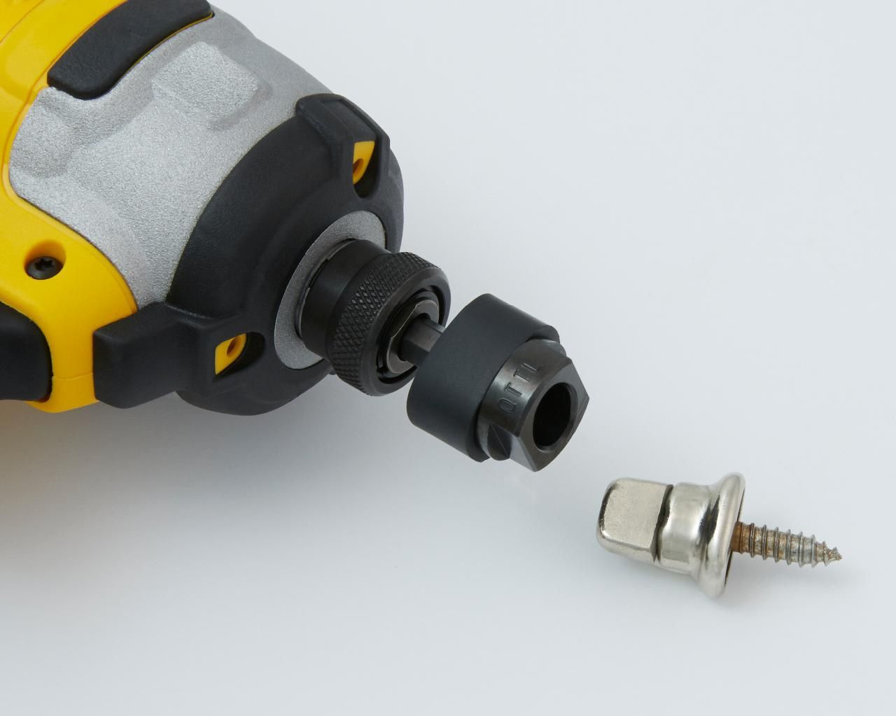 Yellow and silver impact driver with a detached screw attachment and a screw.