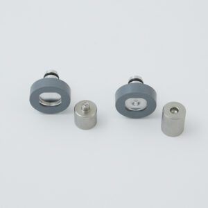 Two sets of mechanical parts: gray rubber rings with steel inserts and cylindrical metal pieces, arranged on a white surface.
