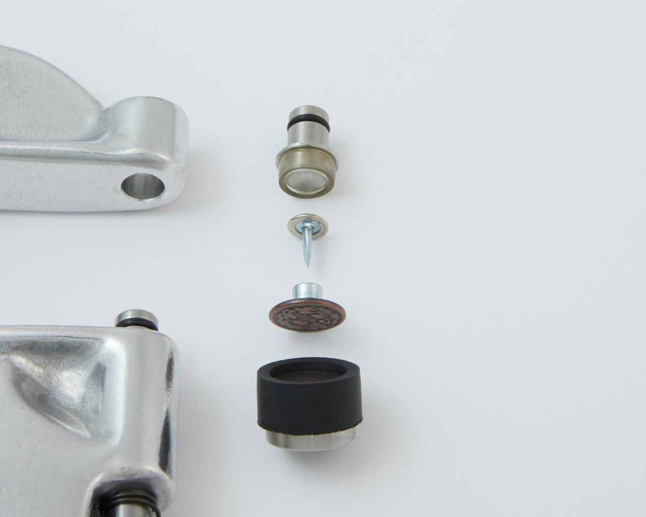 Exploded view of a mechanical component; metal pieces, a bolt, a pad, and a rubber buffer.