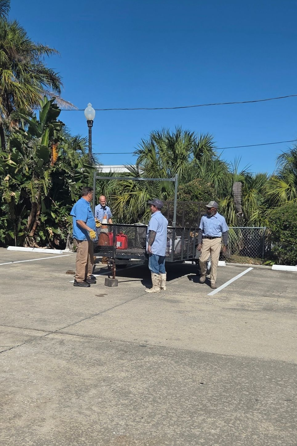 A man in green overalls is mopping the floor next to a caution wet floor sign.