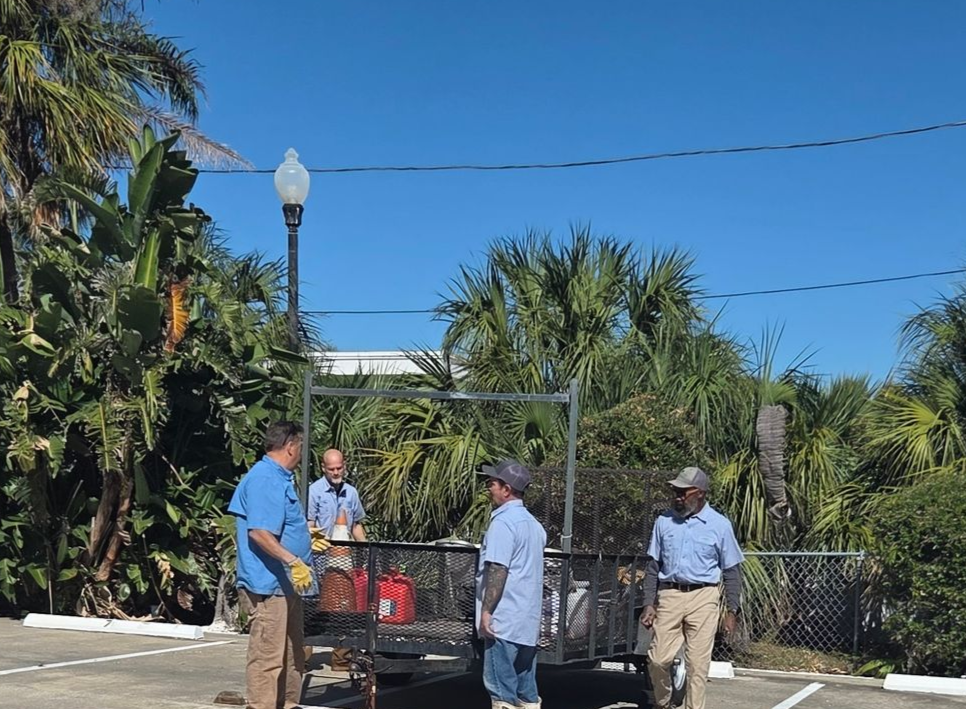 A man wearing a hard hat and a yellow vest is standing with his arms crossed.